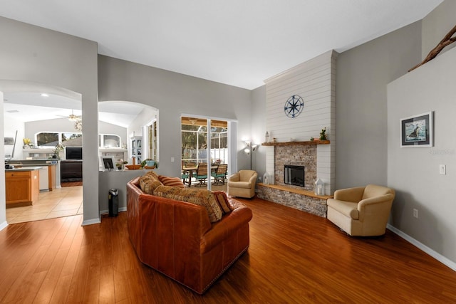 5123 Whispering Leaf Trl, Valrico, FL 33596 - living room featuring a fireplace, arched walkways, a ceiling fan, and light wood-style floors