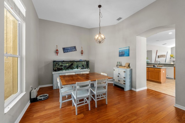 5123 Whispering Leaf Trl, Valrico, FL 33596 - dining area featuring visible vents, light wood finished floors, a chandelier, arched walkways, and baseboards