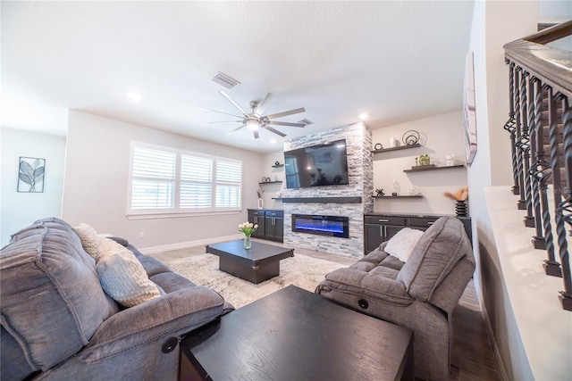 living room featuring visible vents, a ceiling fan, a fireplace, baseboards, and stairs