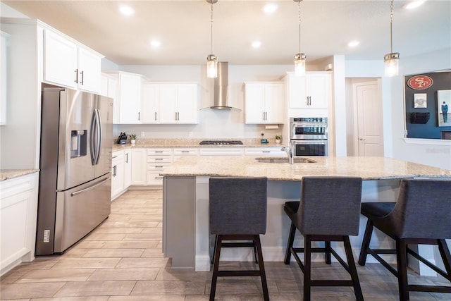 kitchen with a kitchen breakfast bar, appliances with stainless steel finishes, wall chimney exhaust hood, and white cabinets