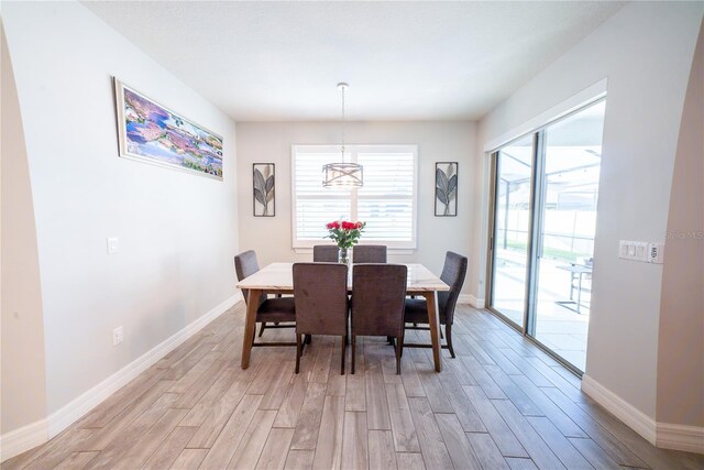 dining room with baseboards, an inviting chandelier, and light wood-style flooring