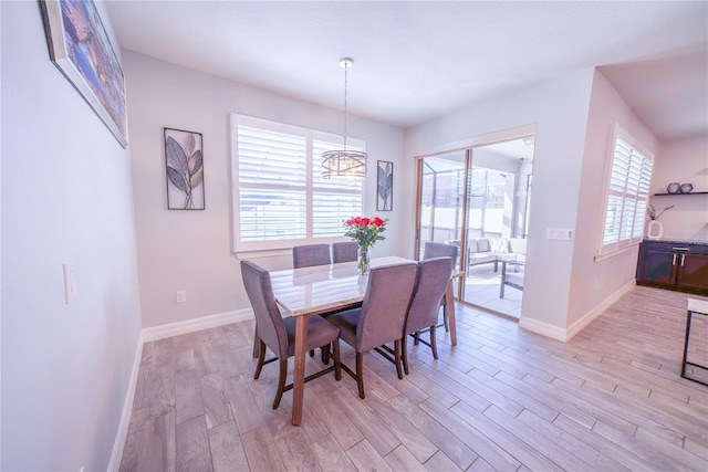 dining area featuring a notable chandelier, light wood-type flooring, and baseboards