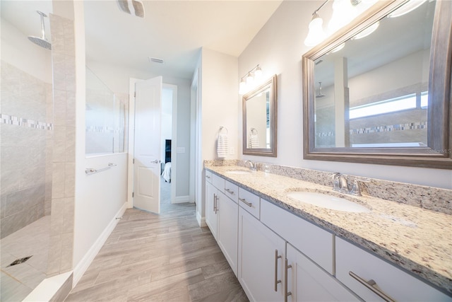full bathroom featuring double vanity, a walk in shower, wood finished floors, and a sink