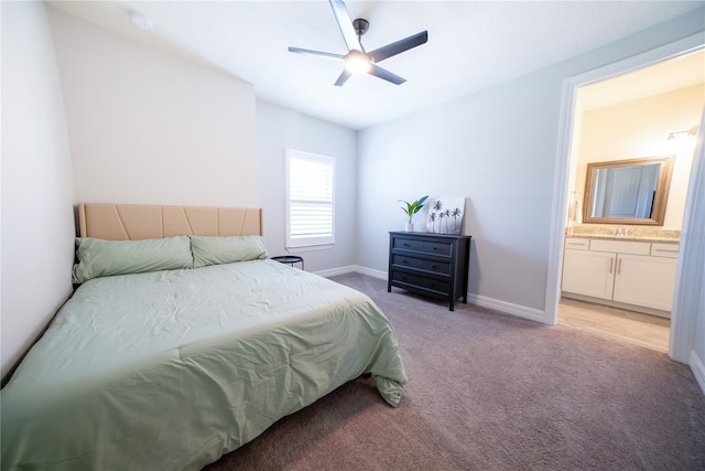 bedroom featuring ceiling fan, baseboards, light carpet, ensuite bathroom, and a sink