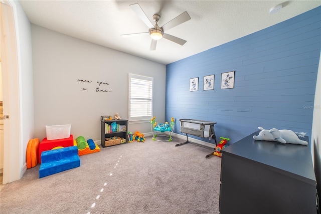 playroom featuring baseboards, a textured ceiling, a ceiling fan, and carpet