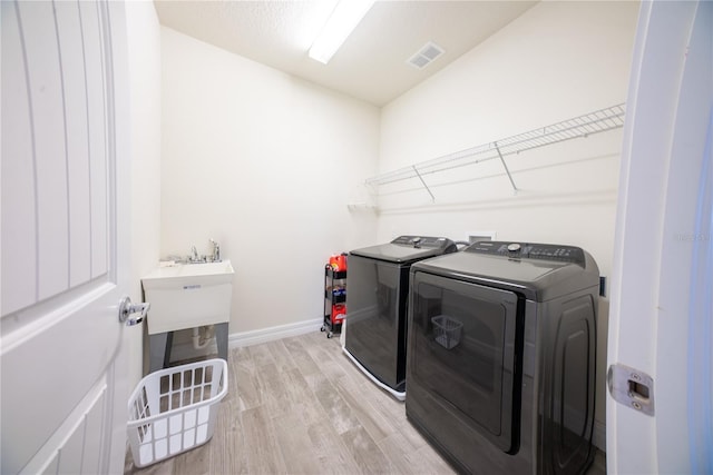 laundry room featuring visible vents, separate washer and dryer, light wood finished floors, baseboards, and laundry area
