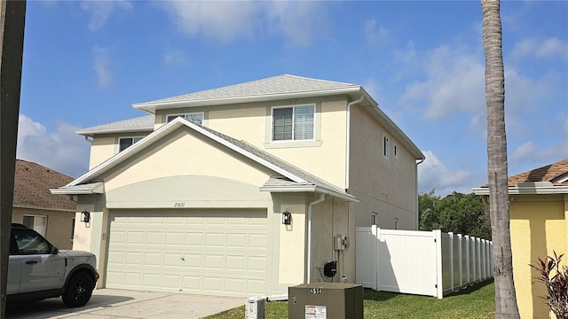 traditional home with stucco siding, driveway, and fence