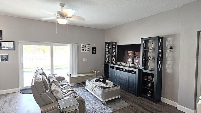 living room featuring dark wood-style floors, baseboards, and ceiling fan