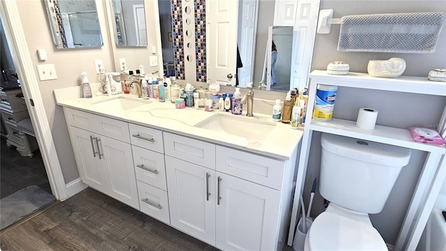 full bathroom featuring double vanity, toilet, wood finished floors, and a sink