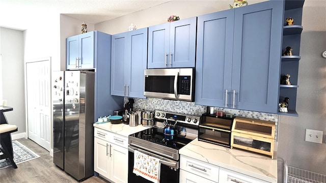 kitchen with light stone countertops, open shelves, blue cabinetry, stainless steel appliances, and light wood-type flooring