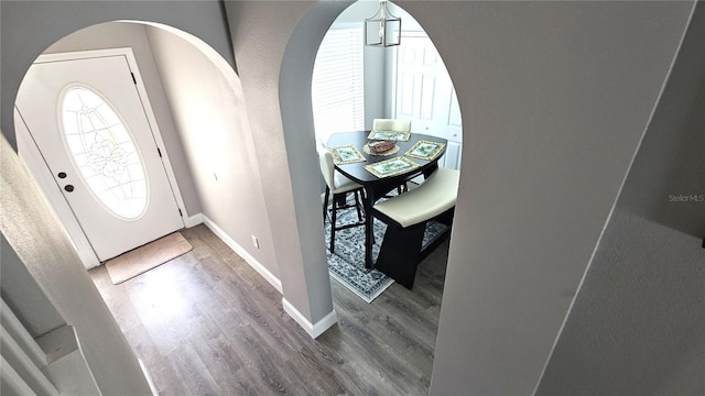 foyer with baseboards, arched walkways, and wood finished floors