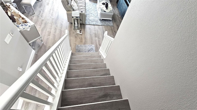 stairway with wood finished floors and a textured wall