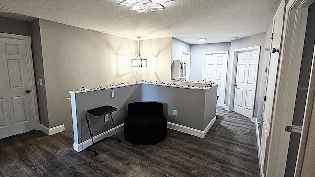 sitting room featuring dark wood finished floors, a textured ceiling, and baseboards