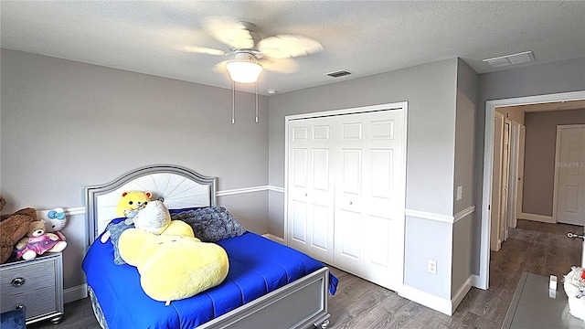 bedroom with wood finished floors, visible vents, a closet, and a textured ceiling