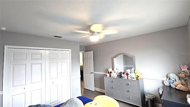 bedroom featuring visible vents, a ceiling fan, a textured ceiling, dark wood-style floors, and a closet