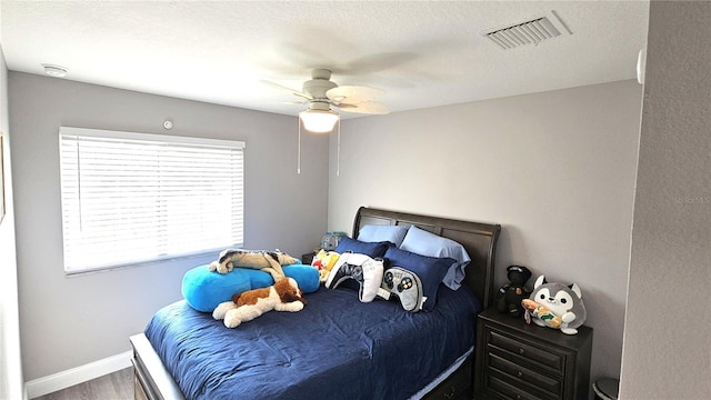 bedroom with visible vents, ceiling fan, baseboards, and wood finished floors