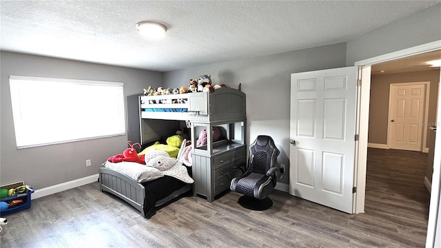 bedroom with baseboards, a textured ceiling, and wood finished floors