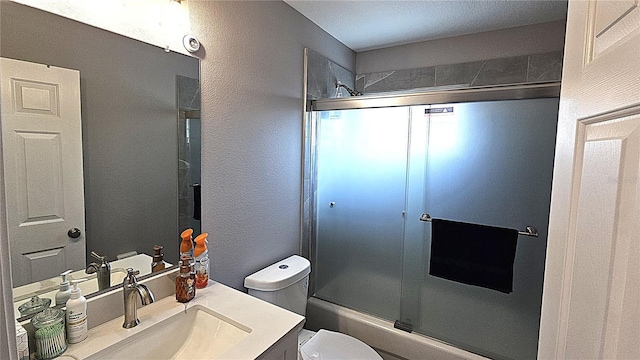 bathroom featuring shower / bath combination with glass door, toilet, vanity, and a textured wall