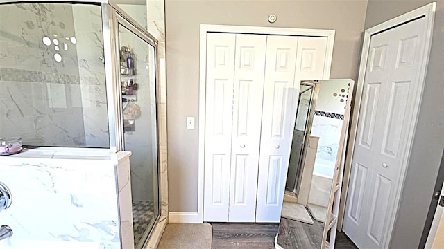 25631 Bruford Blvd, Land O Lakes, FL 34639 - bathroom featuring a closet, a shower stall, a bath, wood finished floors, and baseboards
