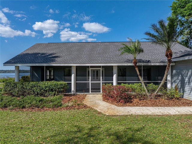 rear view of house with a sunroom, a lawn, and a shingled roof