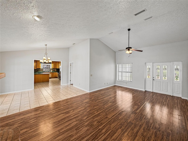 unfurnished living room featuring visible vents, a textured ceiling, light wood-style flooring, and ceiling fan with notable chandelier