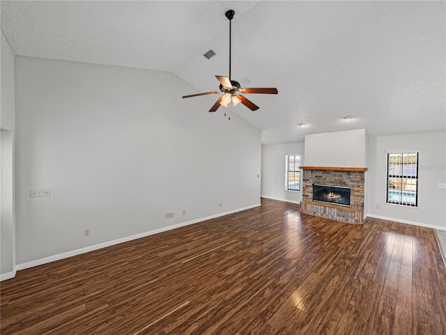 unfurnished living room with a brick fireplace, baseboards, lofted ceiling, wood finished floors, and a ceiling fan