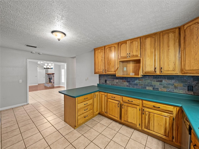 kitchen with a chandelier, light tile patterned floors, decorative backsplash, a peninsula, and brown cabinetry