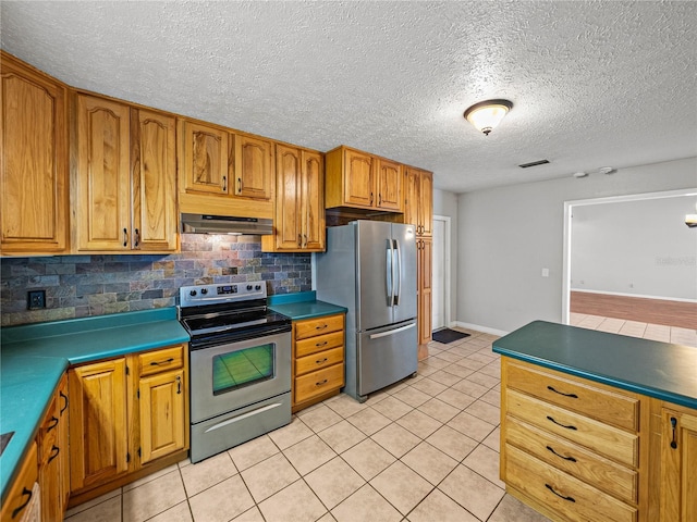 kitchen with tasteful backsplash, under cabinet range hood, light tile patterned floors, appliances with stainless steel finishes, and brown cabinetry