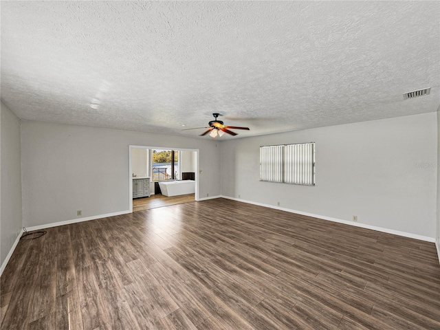 unfurnished room with visible vents, baseboards, wood finished floors, a textured ceiling, and a ceiling fan