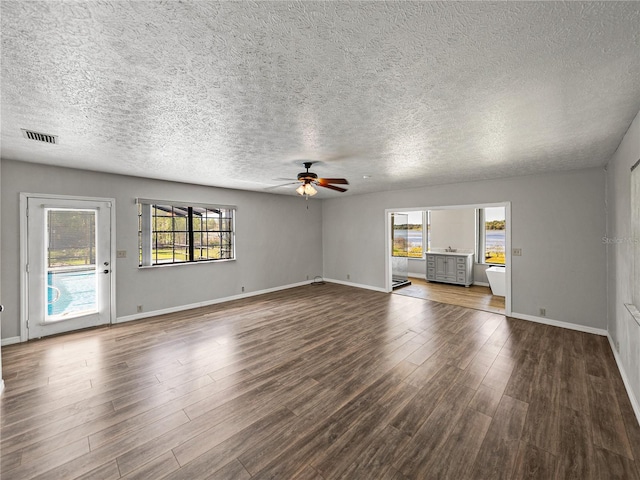 unfurnished living room with baseboards, wood finished floors, visible vents, and ceiling fan
