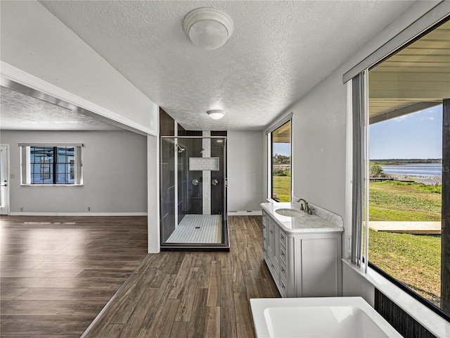 full bath featuring a shower stall, baseboards, vanity, wood finished floors, and a textured ceiling