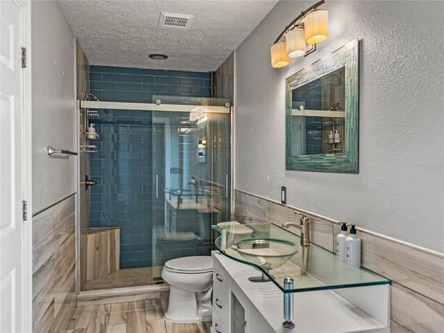 full bathroom with visible vents, a textured ceiling, a stall shower, and a textured wall