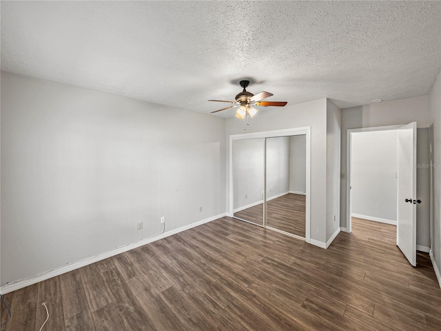 unfurnished bedroom featuring ceiling fan, baseboards, a closet, dark wood-style floors, and a textured ceiling