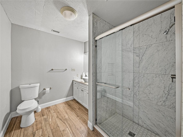 bathroom with vanity, a shower stall, wood finished floors, and visible vents