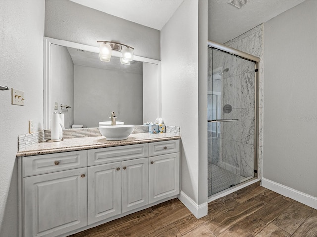 full bath featuring a stall shower, baseboards, wood finished floors, and vanity