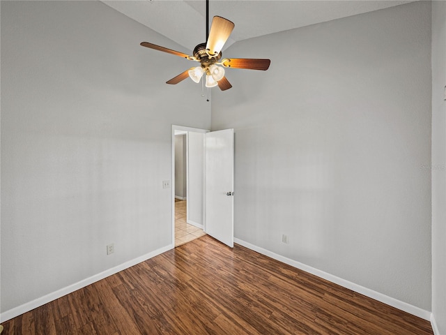 spare room featuring a high ceiling, wood finished floors, baseboards, and ceiling fan