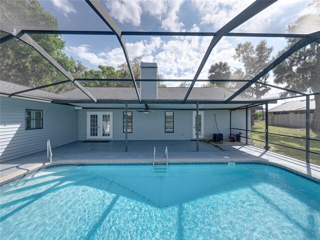 outdoor pool with a patio area, glass enclosure, french doors, and a ceiling fan