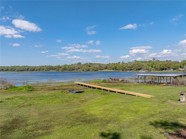 view of dock with a yard and a water view