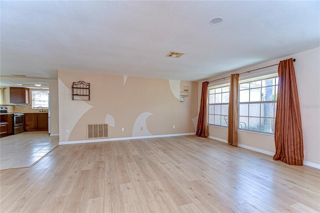 interior space featuring a sink, visible vents, baseboards, and light wood-style floors