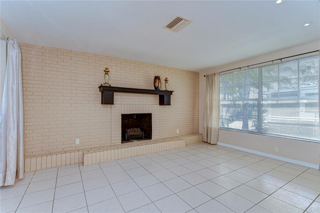 unfurnished living room featuring tile patterned flooring, visible vents, brick wall, baseboards, and a fireplace