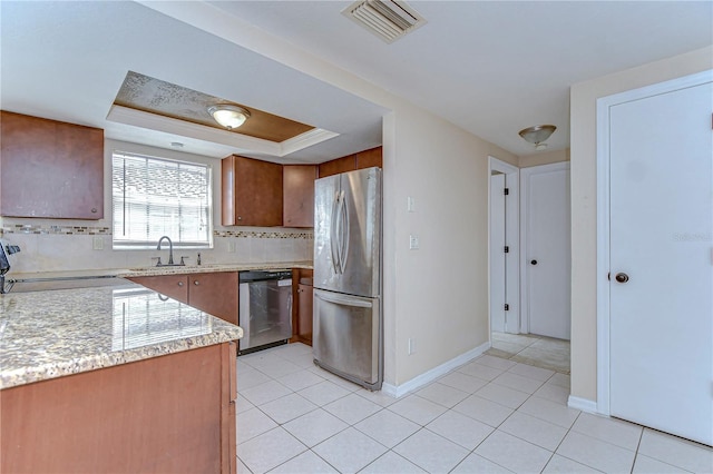 kitchen featuring visible vents, a tray ceiling, backsplash, stainless steel appliances, and light countertops