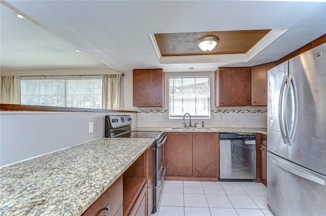 kitchen with a sink, tasteful backsplash, stainless steel appliances, light tile patterned floors, and a raised ceiling