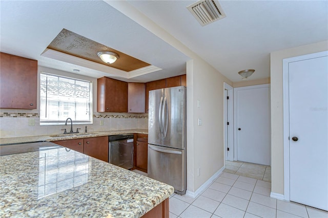 kitchen with visible vents, a sink, stainless steel appliances, a raised ceiling, and backsplash