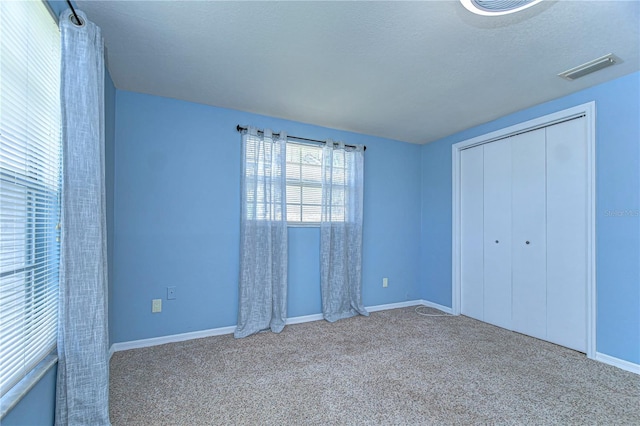 unfurnished bedroom featuring visible vents, baseboards, carpet, a closet, and a textured ceiling