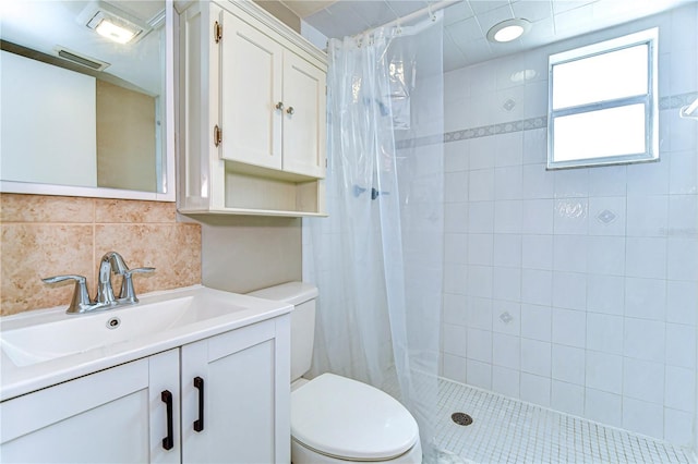 bathroom featuring vanity, visible vents, a tile shower, toilet, and backsplash