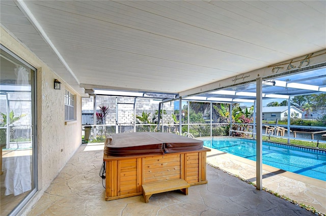 outdoor pool featuring a patio area, glass enclosure, and a hot tub