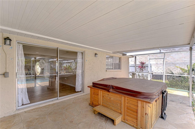 view of patio featuring glass enclosure and a hot tub