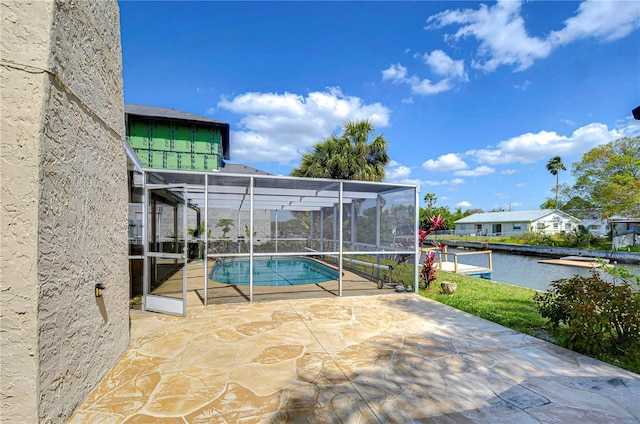 outdoor pool featuring glass enclosure, a patio area, and a water view