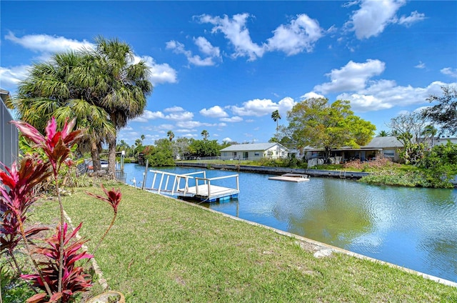 view of dock with a lawn and a water view