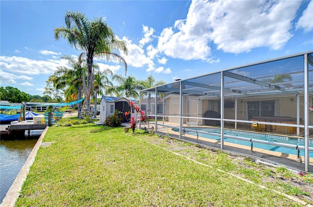 view of yard featuring a water view, a shed, an outdoor structure, an outdoor pool, and a lanai